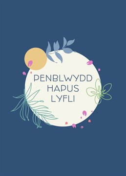 Welsh language card featuring 'Happy Birthday Lovely' surrounded by a beautiful wreath of plants and flowers.